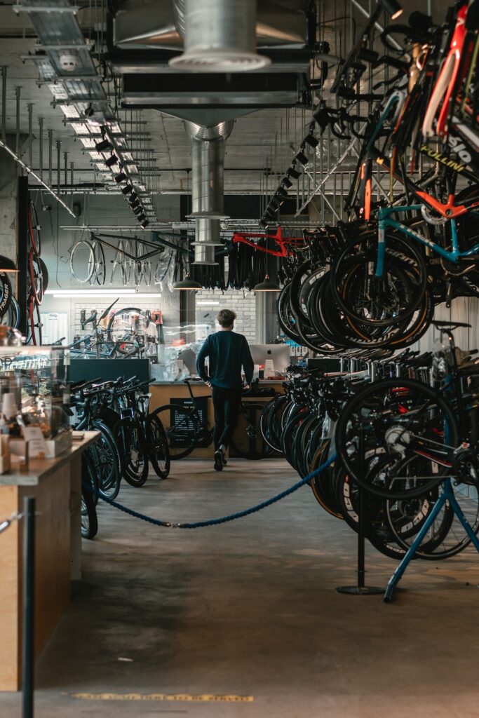 A bicycle store with mountain bikes hanging from wall racking and a servicing area with equipment obtained via an equipment loan in the background.