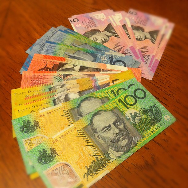 A photograph of Australian Dollars lined up in domination on a wooden table